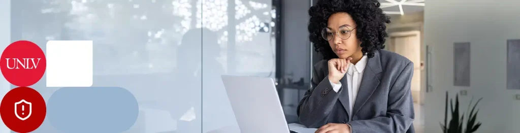 Person in a suit working on a laptop in a bright office setting.