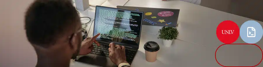 Person coding on a laptop in a professional workspace with another laptop, coffee cup, and plant