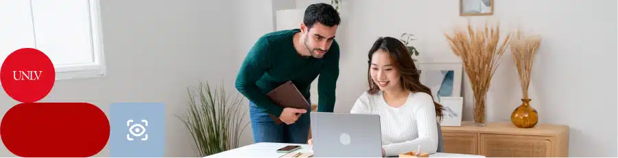 Two people collaborating at a desk with a laptop and tablet in a modern office setting