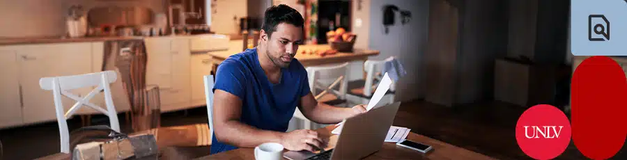 working on the computer while holding a paper about something that's Beyond the A+ Certification, Your Cybersecurity Career Path